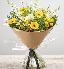 Bernard Chapman hand-tied fresh flower bouquet - ‘Lemon Drizzle’. Featuring white stocks, ivory large headed roses, yellow germini, yellow spray chrysanthemums, lemon alstroemeria and yellow solidago with pistache, salal and birch. (Code: S33240MS)